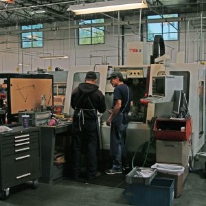 Two operators consulting on a job being run on one of the Bridgeport CNC mills.