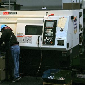 A CNC lathe operator monitors progress of a job.